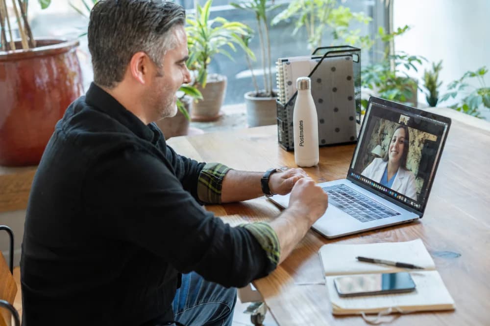 A patient meeting a licensed clinician over a video visit on a laptop